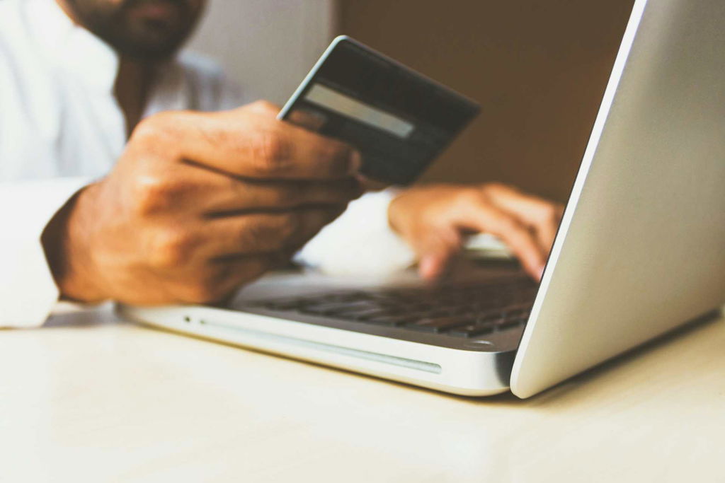 person holding credit card and using a laptop