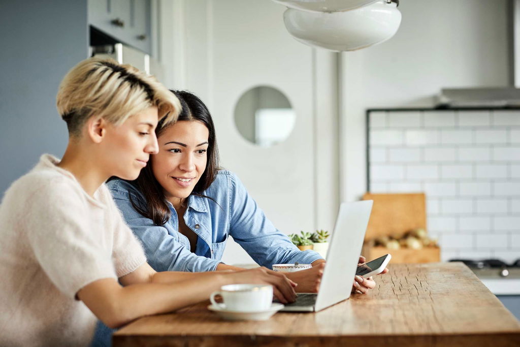 two friends sitting in front of laptop