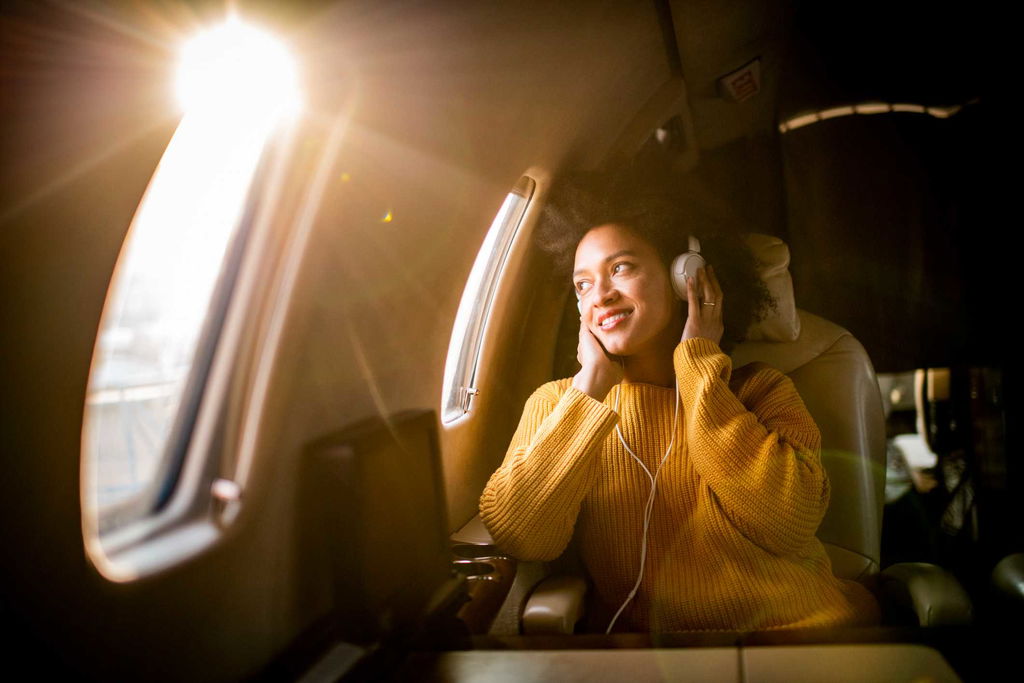 woman on plane with headphones, looking out the window